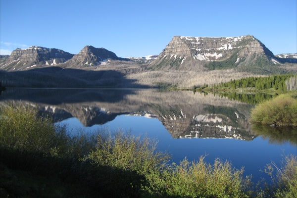 trappers lake reflects burned forest and mountains beyond.