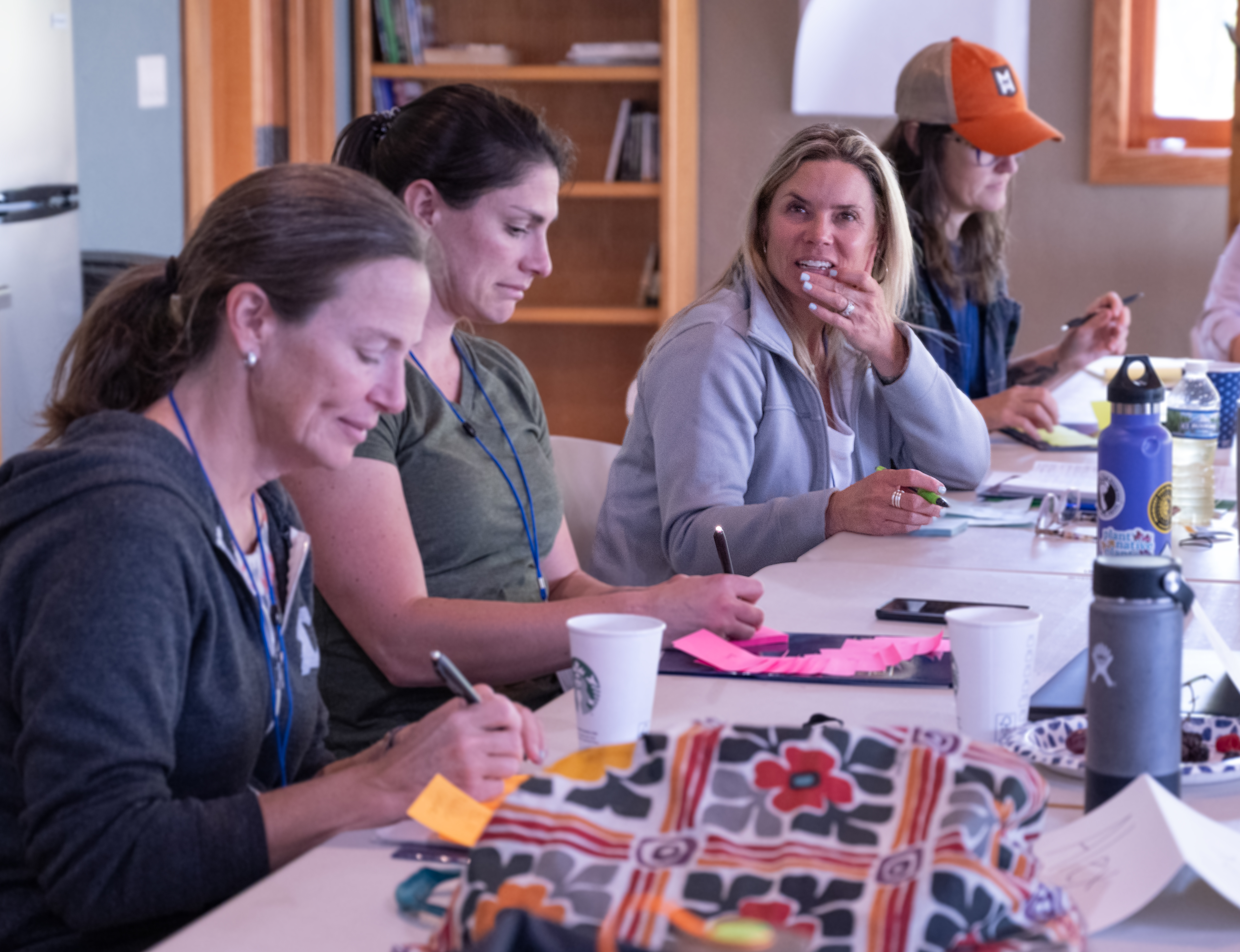 Women work on group project at long conference table.