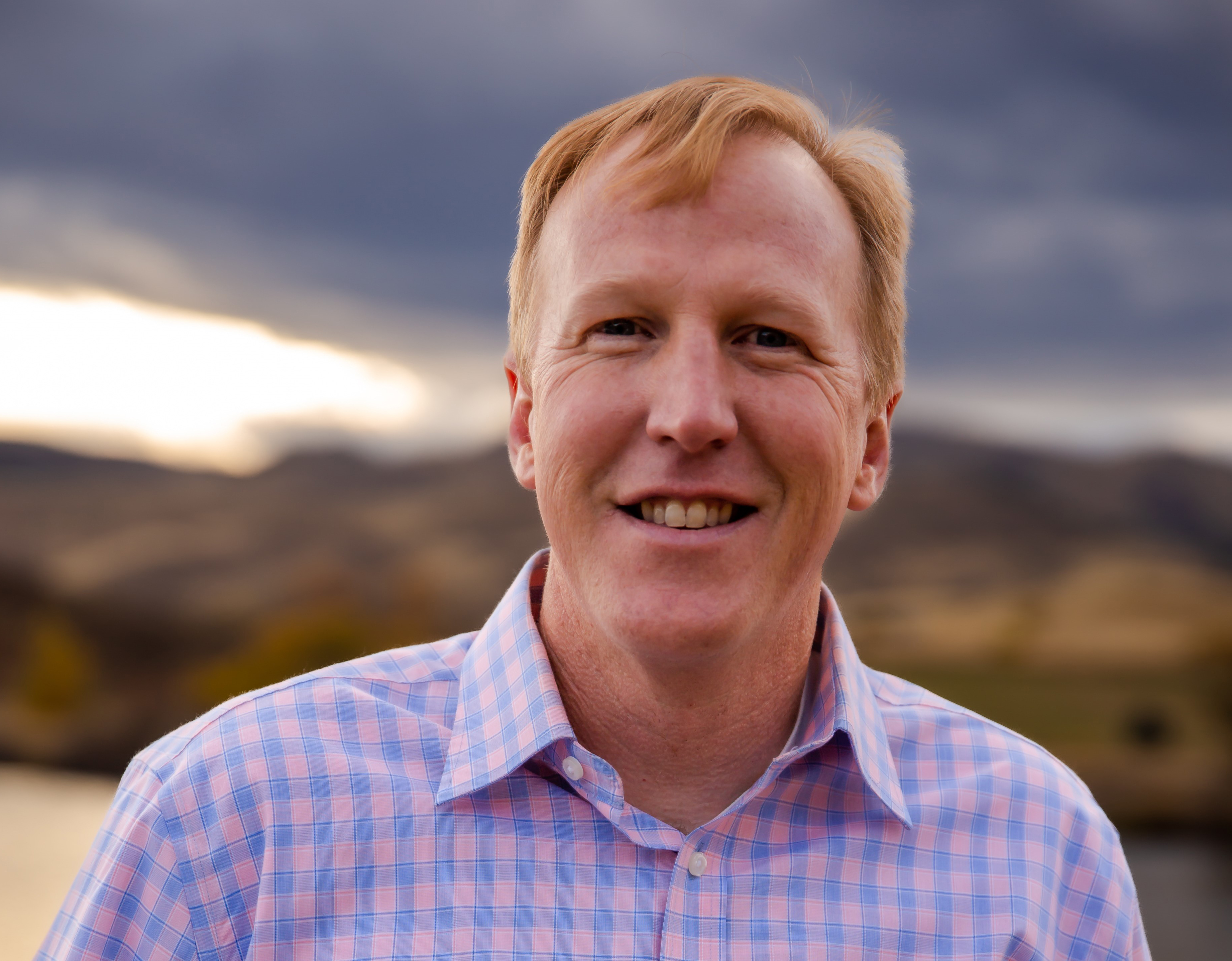 Man with strawberry blonde hair smiles at camera